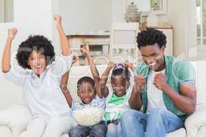 Happy family watching television eating popcorn