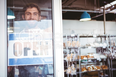 Smiling worker putting up open sign