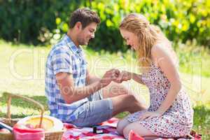 Young man putting on ring during marriage proposal