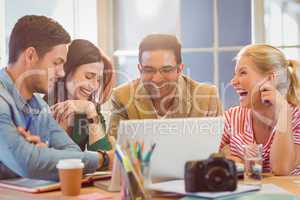 Happy creative business team using laptop in meeting