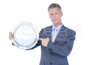 Businessman holding and showing a clock