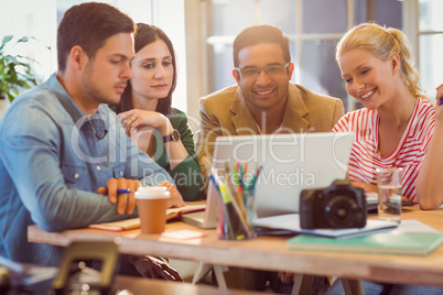 Happy creative business team using laptop in meeting