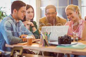 Happy creative business team using laptop in meeting