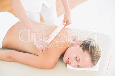 Therapist waxing womans back at spa center