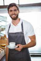 happy worker in apron holding a cup of coffee
