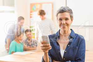 Casual businesswoman using her smartphone and smiling at camera