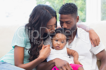 Happy couple with their baby girl on couch