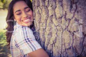 Pretty brunette hugging tree