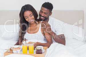 Relaxed couple having breakfast in bed together