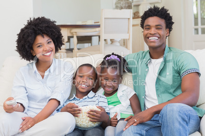 Happy family watching television eating popcorn