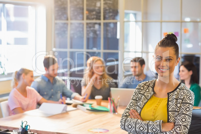 Smiling businesswoman with colleagues in background at office