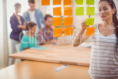 Concentrated businesswoman pointing post its on the wall