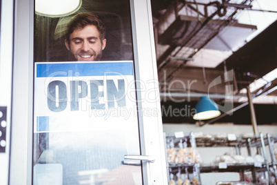 Smiling worker putting up open sign