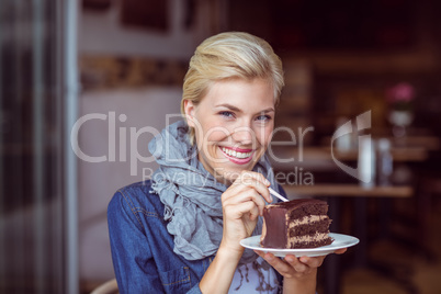 Smiling blonde taking a piece of chocolate cake