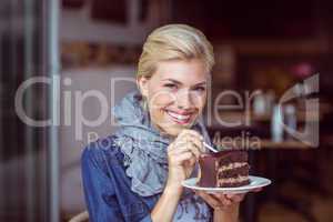 Smiling blonde taking a piece of chocolate cake