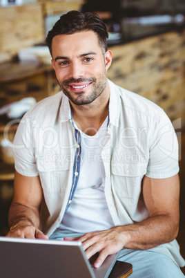 Happy young businessman working at laptop drinking coffee