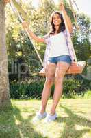 Pretty brunette swinging in park