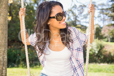 Pretty brunette swinging in park