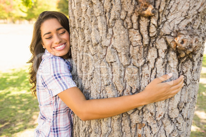 Pretty brunette hugging tree