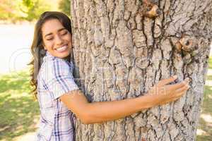 Pretty brunette hugging tree