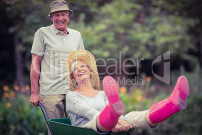 Happy senior couple playing with a wheelbarrow