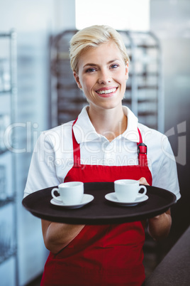 Pretty barista holding two cups of coffee