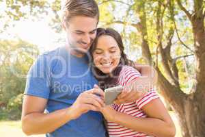 Cute couple using mobile phone in the park