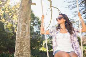 Pretty brunette swinging in park