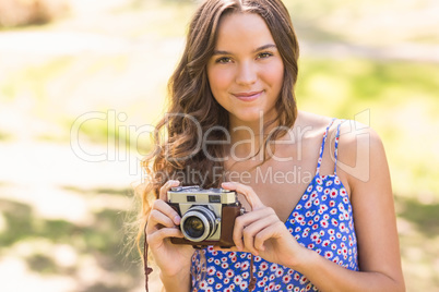 Pretty brunette in the park using retro camera