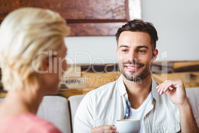 Couple with coffee cup sitting on sofa