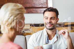 Couple with coffee cup sitting on sofa