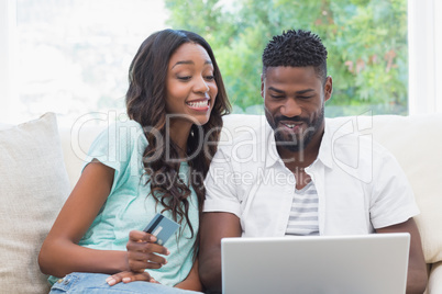 Happy couple on the couch shopping online