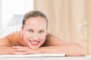 Peaceful blonde lying on towel smiling at camera