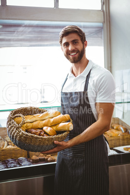 Portrait of happy worker holding basket of bread