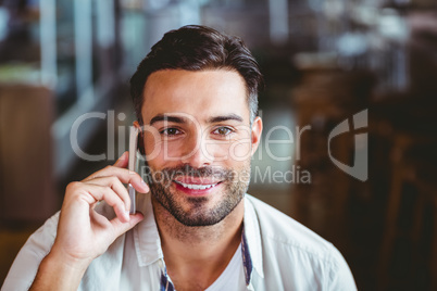 Smiling man on the phone having coffee