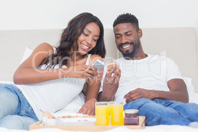 Relaxed couple having breakfast in bed together