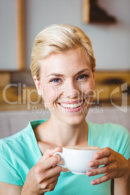 Pretty blonde looking at camera and holding cup of coffee