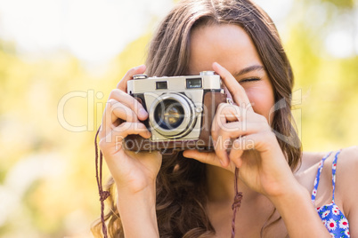 Pretty brunette in the park using retro camera