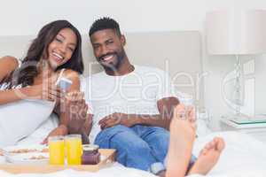 Relaxed couple having breakfast in bed together