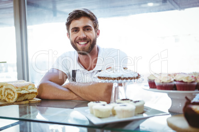 Smiling worker posing behind the counter arm crossed