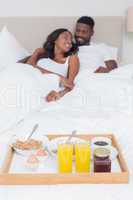 Relaxed couple having breakfast in bed together