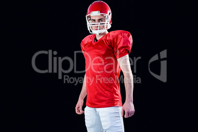 A serious american football player taking his helmet looking at