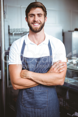 Smiling server in apron arm crossed