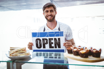 Smiling worker putting up open sign