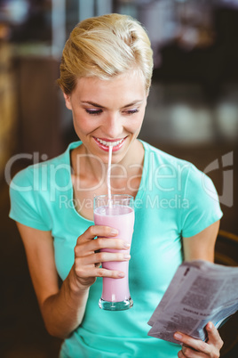 Smiling blonde woman enjoying her milkshake