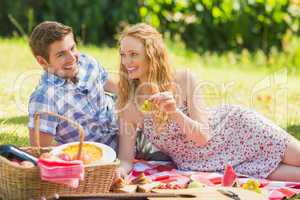 Young couple eating grapes at a picnic