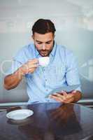 Businessman drinking coffee while watching tablet