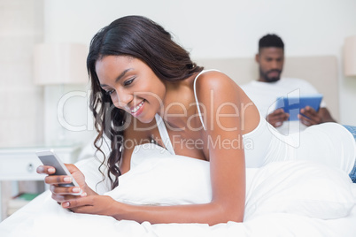 Relaxed couple using technology on bed