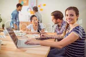 Smiling young businesswoman using laptop