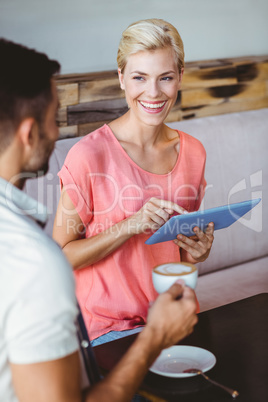 Happy blonde woman using tablet and looking her boyfriend